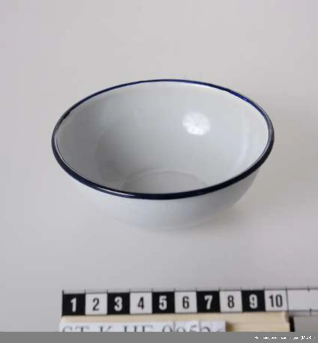 Hvitemaljert liten skål med mørkeblå pyntekant øverst.