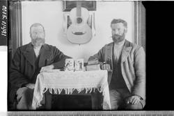 Portrett av to menn som sitter ved et bord.