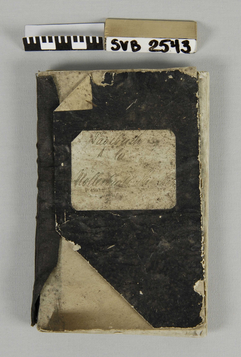 Notatbok med omslag i sort papir, sort tekstilrygg. Hvitt etikett med påskrift i blekk.