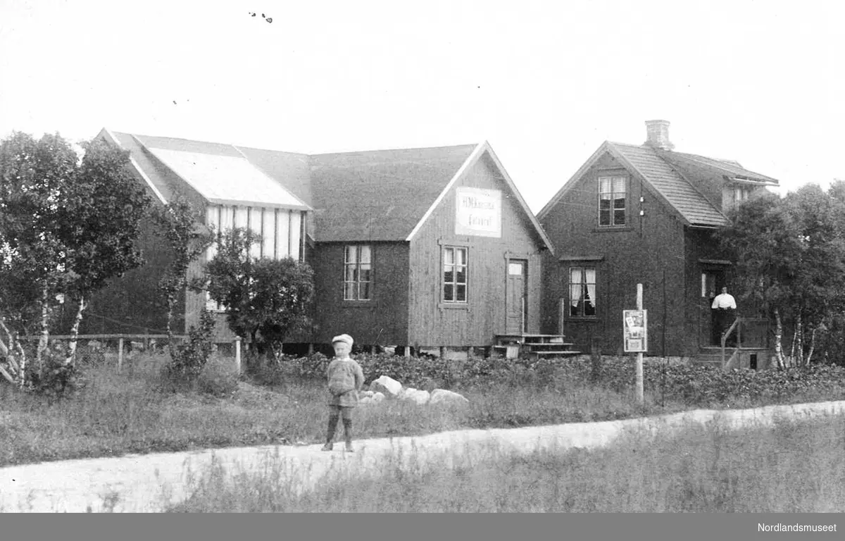 Hans M. Kanstads atelier og bolighus. Atelieret ble ferdig i 1912. I 7 år hadde han drevet teltatelier. Boligen til høyre med en kvinne på trappen. Atelieret til venstre. Gjerde og en del busker samt en vei hvor en gutt står.