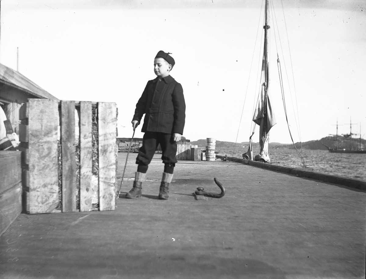 Gutt ved kasse på Dampskipsbrygga i Kragerø