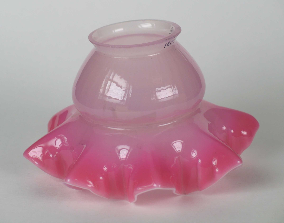 Rosa lampeskjerm i glass med bølget kant nederst.