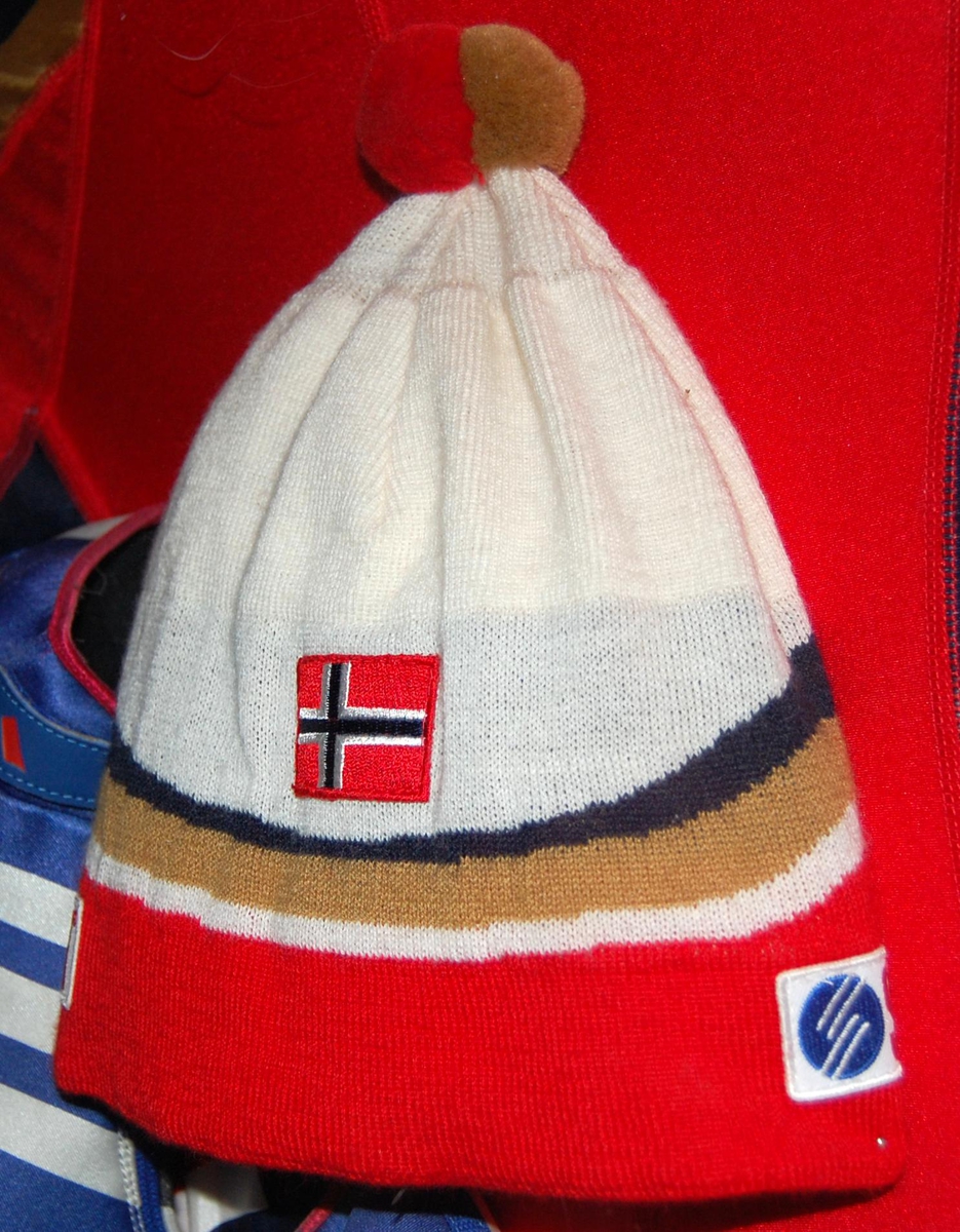 Flerfarget lue med et merke med motiv av det norske flagget. Det er også to merker med logo for Swix på luen. Luen har dusk.