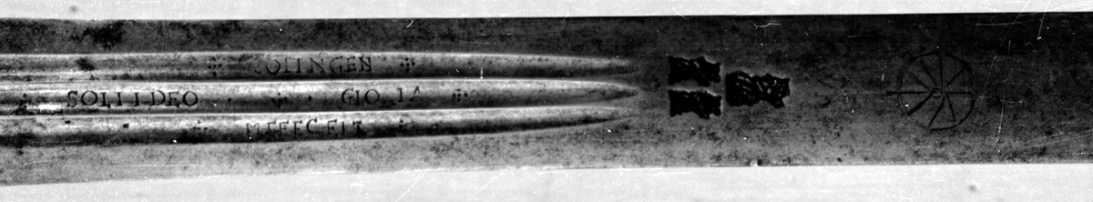 Skarprettersverd.  Pæreformet knapp med fasettetert dekor.
Tregrep viklet med rokkeskinn. 
Rette åttekantede parérstenger som ender i to dråper med kantet dekor. Rett tveegget klinge med ovalt tverrsnitt  og tre korte blodrender på hver side. Innslått tre smedstempler med kronede hoder.  På den ene siden er det gravert inn et hjul og på den andre siden en galge. Begge inngraveringer er innlagt med kobber.

