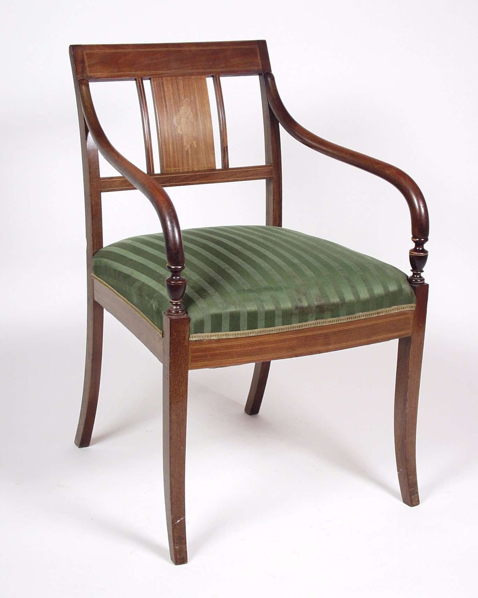 Stolen er av tre med intarsia i rygg.Stolen har stoppet sete i grønt ulltrekk, armlenene er av nøttetre.