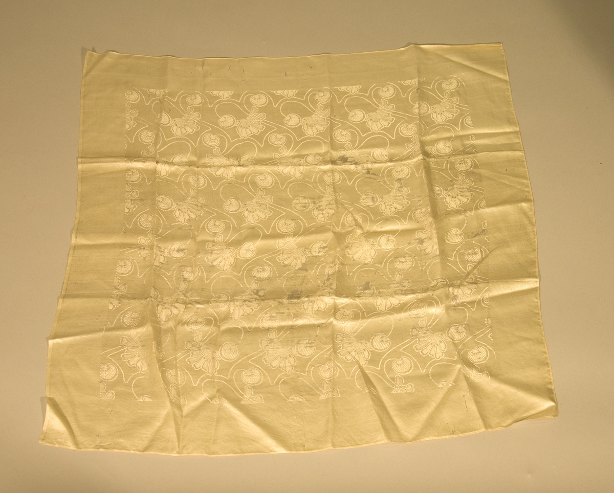 Tørkle av hvit silke med maskinsydd fald på tre sider. Tørkledet har skader.