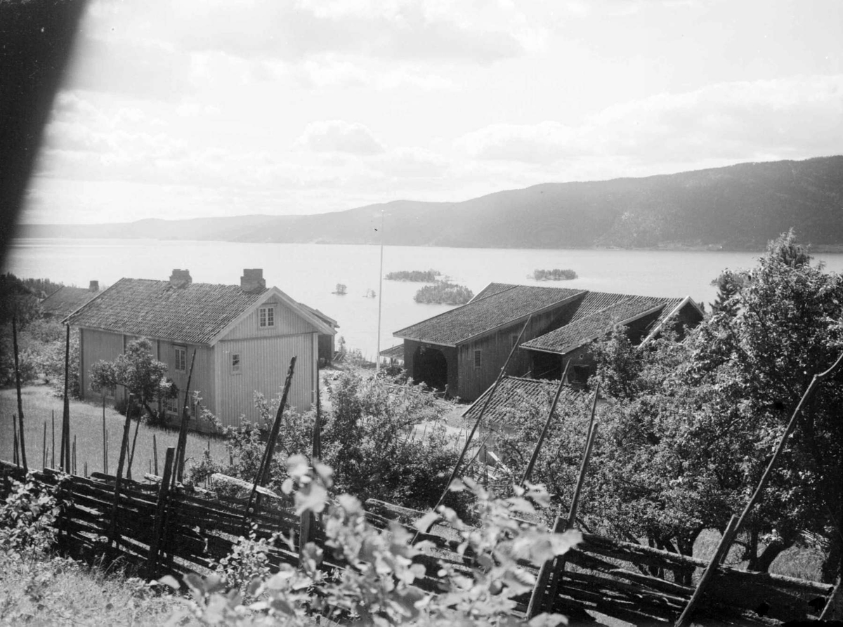 Landskap med våningshus og driftsbygning. Randsfjorden i bakgrunnen.