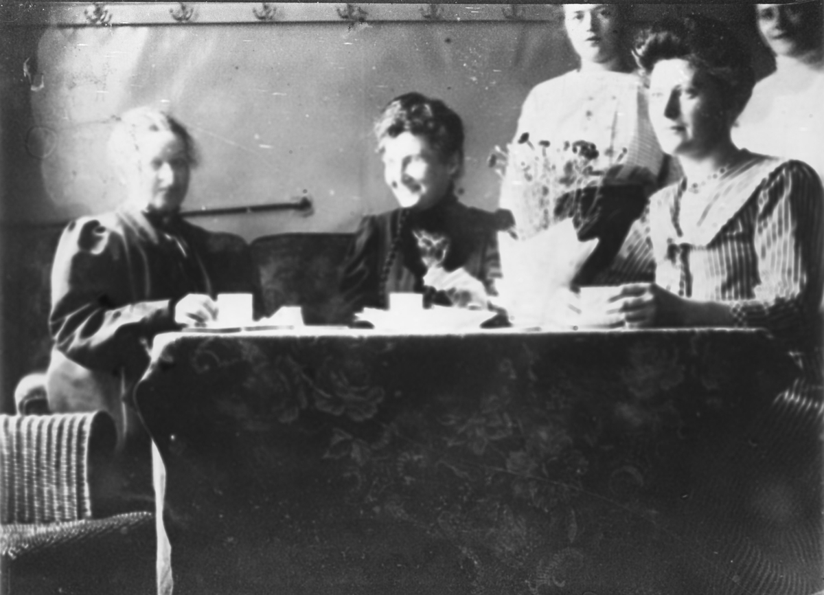 Hjemmenes Vels kjøkken. Kvinner drikker kaffe ved pent oppdekket bord.