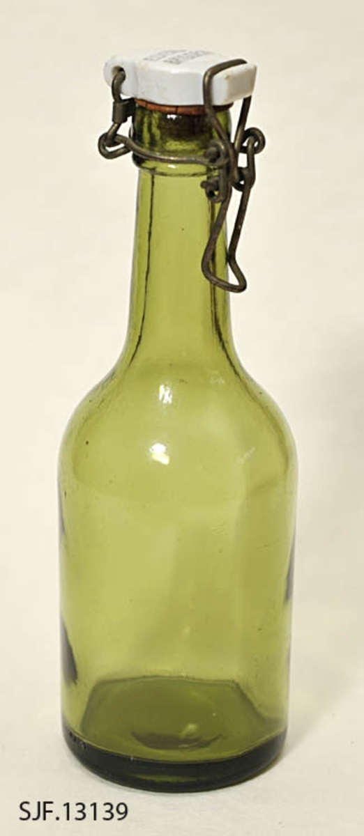 Flaske av grønt glass, antakelig opprinnelig brus- eller ølflaske, som kan ha vært gjenbrukt til aldre drikkevarer, for eksempel husholdningssaft. Flaska er 20,0 centimeter høy (uten kork). Den har en sylindrisk kropp med cirka 7,0 centimeters diameter. Cirka 10 centimeter fra standflata går den sylindriske delen over i ei innoverskrånende skulder mot en mer sylindrisk hals. Den midtre delen av flaskebotnen er oppoverkuvet. Flaska kan romme cirka 3 desiliter væske. Godset omkring munningen - «flasketuten» - er noe tjukkere enn i flaska for øvrig, og her er det et spor som har gitt feste for en såkalt «patentkork». Dette er en propp, utført i kvitt porselen, som er hengslet til flasketuten ved hjelp av ståltråd, som er forankret i det nevnte sporet omkring flasketuten slik at proppen faller ned i flaskemunningen og kan låses der ved hjelp av ei ståltrådspenne, som når flaska lukkes omslutter en tapp i den fremre enden av porselenselementet. Undersida av denne komponenten har vært utstyrt med en rødfarget gummipakning, som skulle skape et vakuum i flaska. Her er pakningen bare delvis intakt. Oversida av porselenselementet er merket «ELVERUM BRYGGERI» (jfr. fotografiet SJF-F.013394).