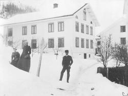 To kvinner og en mann foran tjenerboligen på Berg gård, Brøt