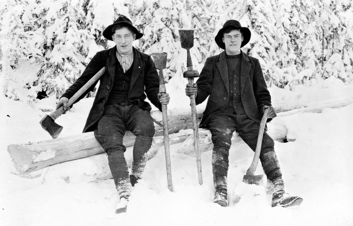 2 tømmerhuggere med store hatter, øks og berkjespade i Ulvemarka, Brøttum, Ringsaker. Fra venstre er Johann Svendsrud, Maurits Antonsen Sæther f.1896.