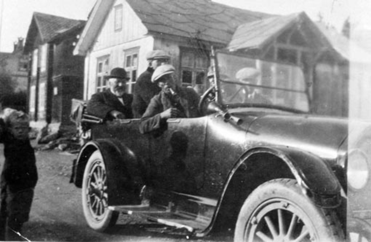 Karl Berntsen's (1893-1967) første drosjebil. Buick. Passasjerene er Johannes og Ole Bevolden. Tur til Fåvang. Bilde tatt i Fåvang sentrum, huset bak bilen er Lesjøs første bakeri, så Helga Østvangs hus, i bakgrunnen litt av O.P. Nordrums butikk