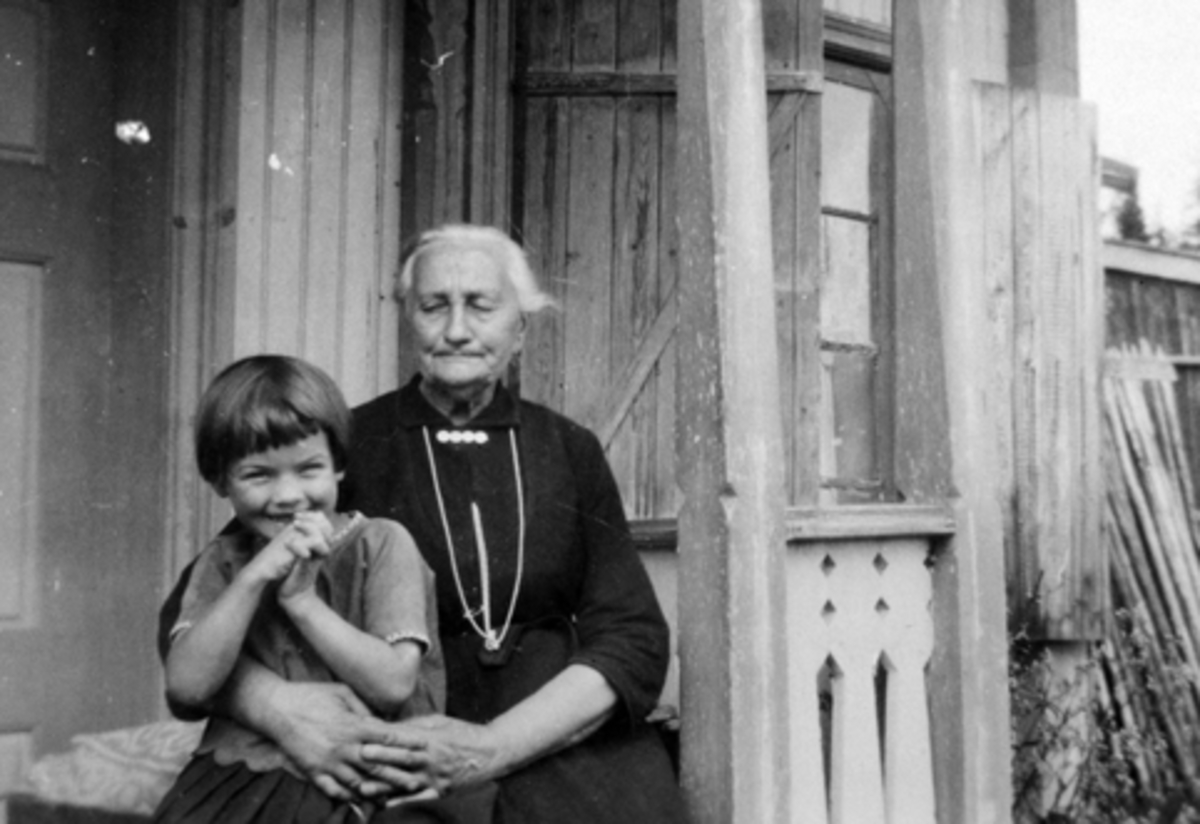 Budeie Anne Berg (1853-1931) med Ingrid Feiring (1922-1946) på fanget utenfor huset i Borkerud.