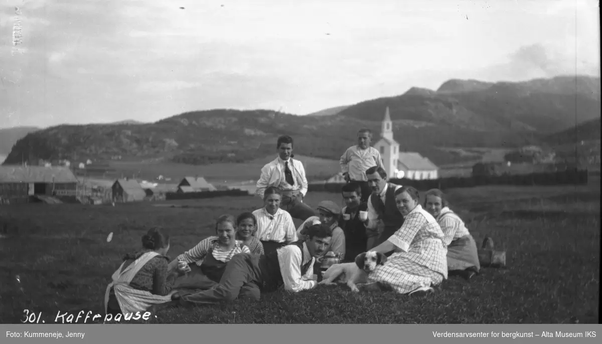 Gruppebilde fra kaffepause i landskap. Talvik kirke i bakgrunnen. 1920