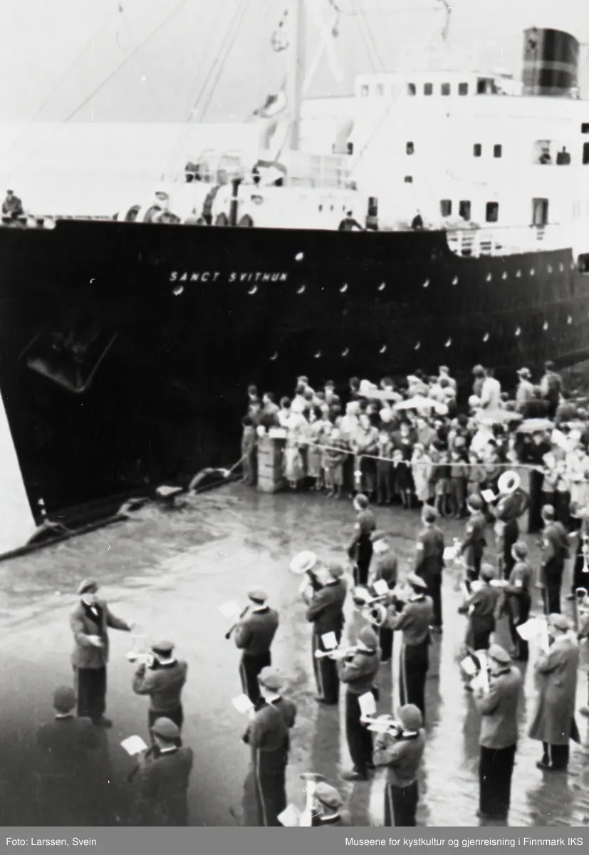 Nordkappfestivalen 1956. Lord Fraser of North Cape blir mottatt av Honningsvåg Guttemusikk og Honningsvåg Musikkforening på dampskipskaia. Hurtigruteskipet 'Sanct Svithun' ved kaia.