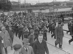 Hamar guttemusikkorps marsjerer fra jernbanestasjonen og ove