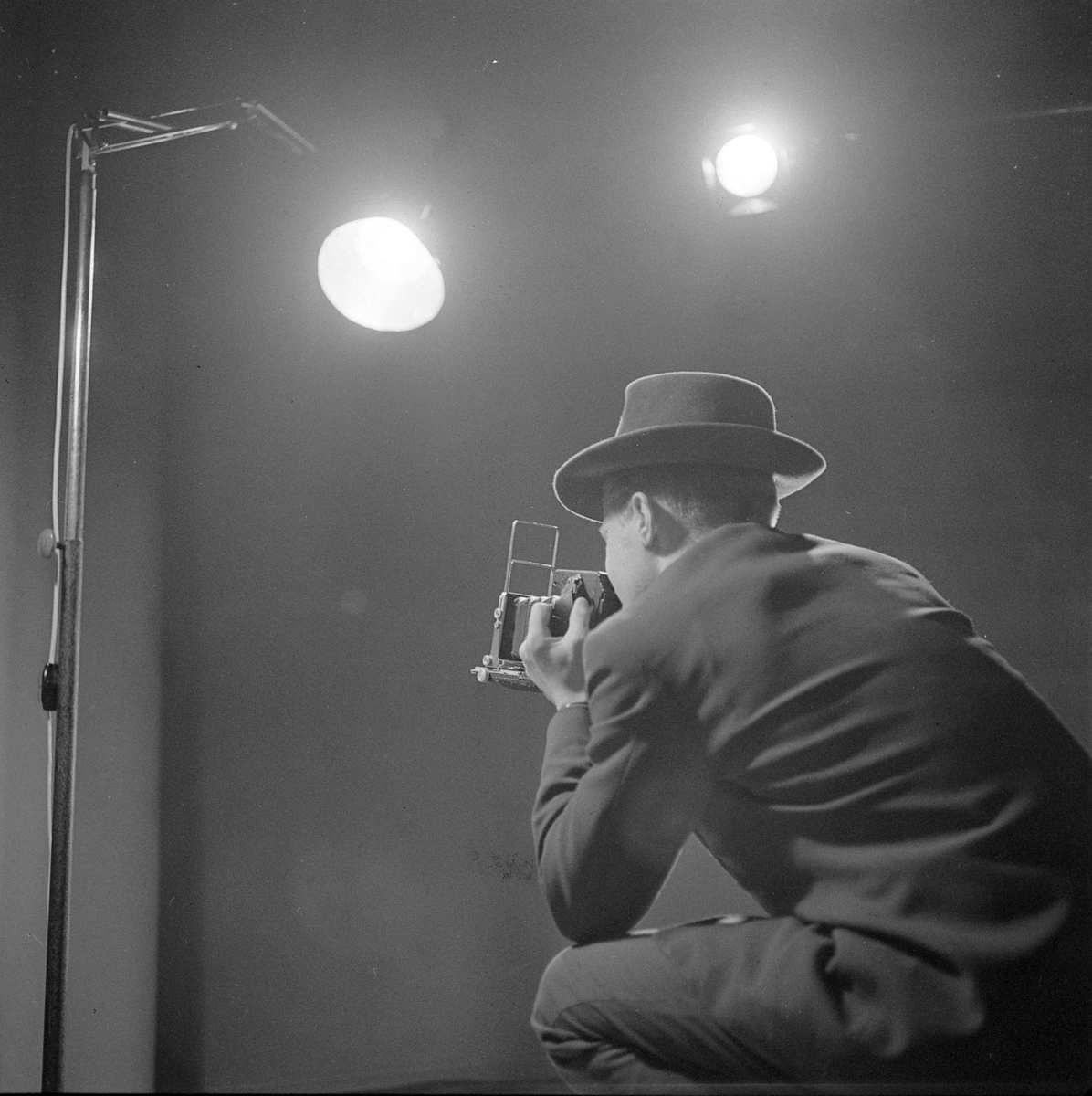 Fotograf med Speed Graphic pressekamera i fotostudio