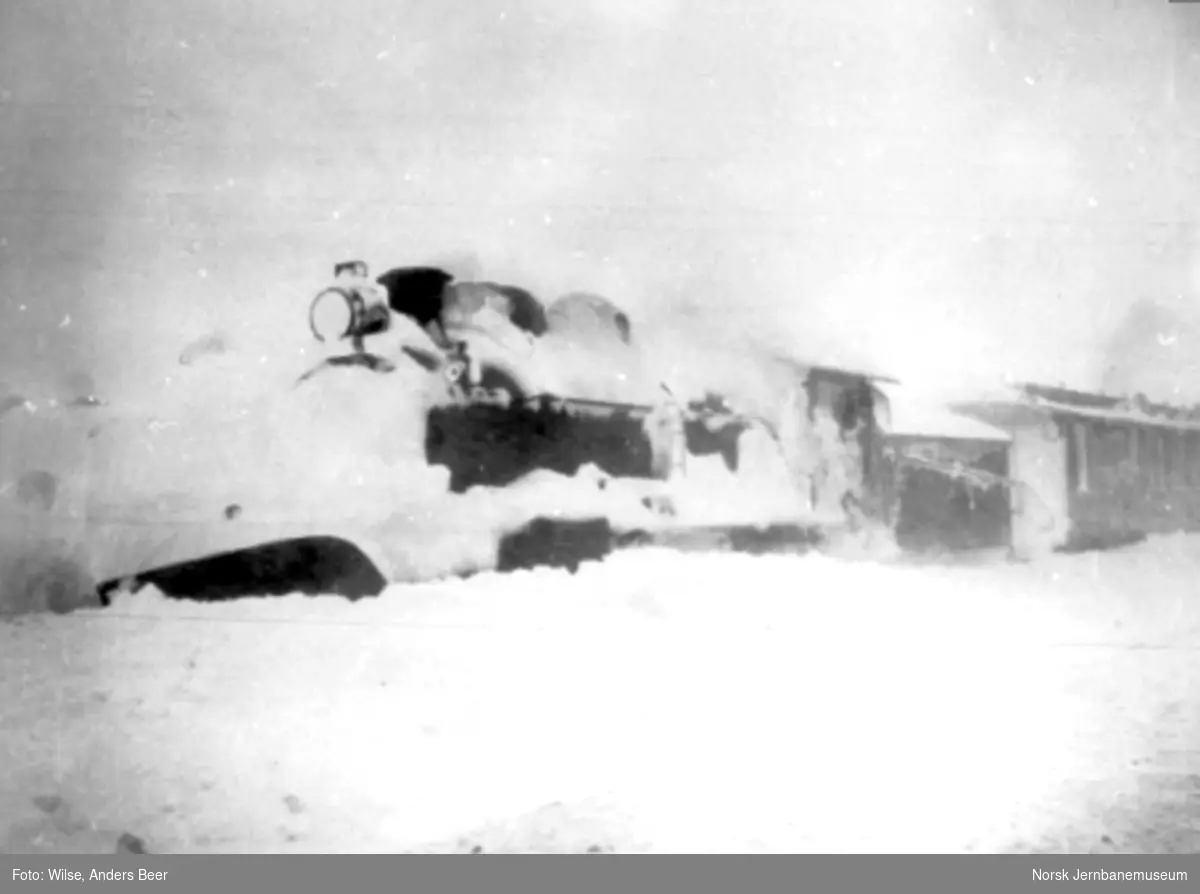 Nedsnødd damplokomotiv type 22a foran en personvogn