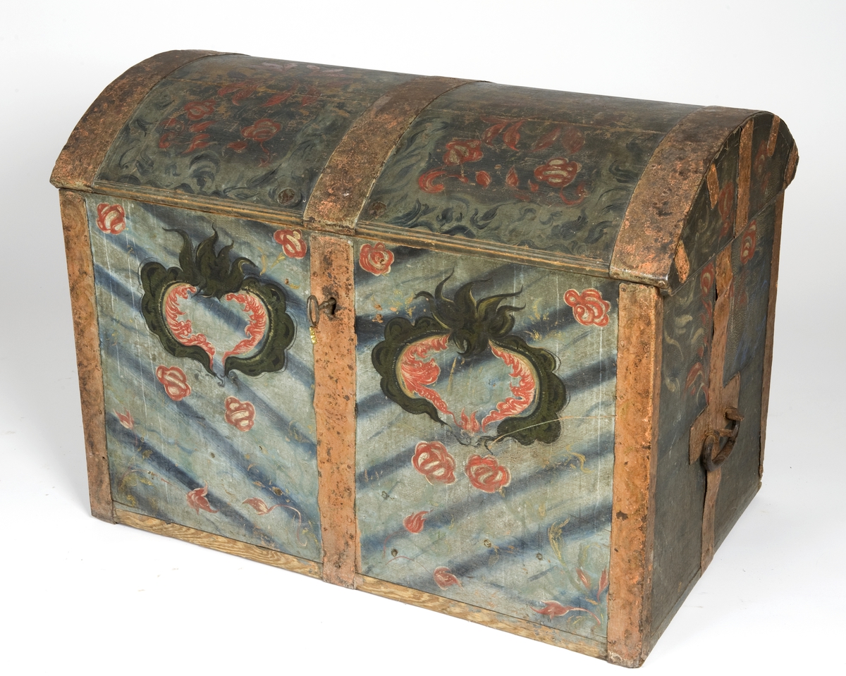 Kiste med buet lokk og smijernsbeslag og bånd. Rosemalt lokk og tre sider. Innvendig rosemaling delvis vasket bort.