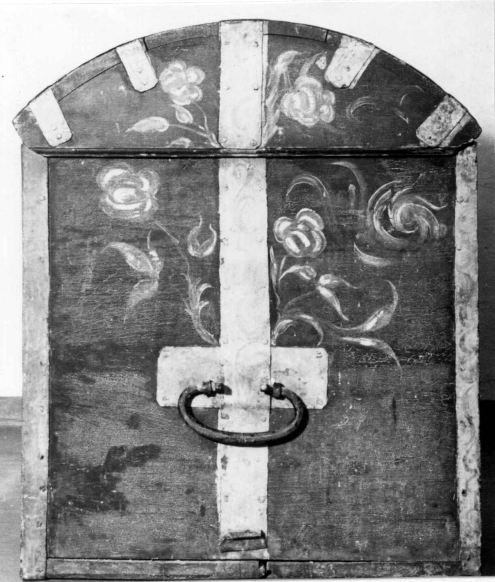 Kiste med buet lokk og smijernsbeslag og bånd. Rosemalt lokk og tre sider. Innvendig rosemaling delvis vasket bort.