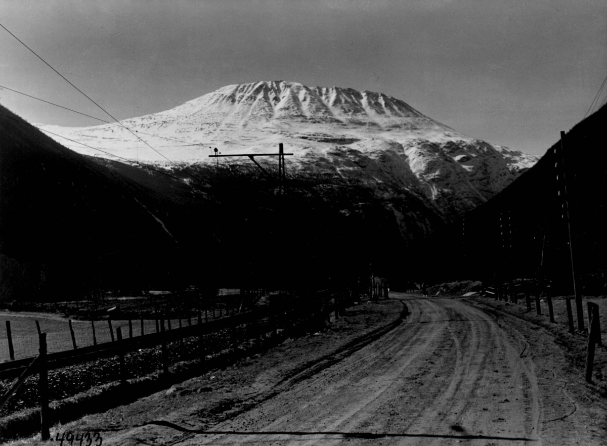 Jernbane og vei med Gaustatoppen i Vestfjorddalen i bakgrunnen.