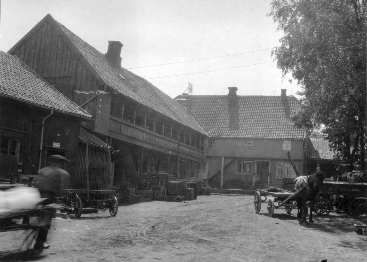 Moss, Østfold. Bygninger ved gårdsplass med kasser og hestekjøretøy.
