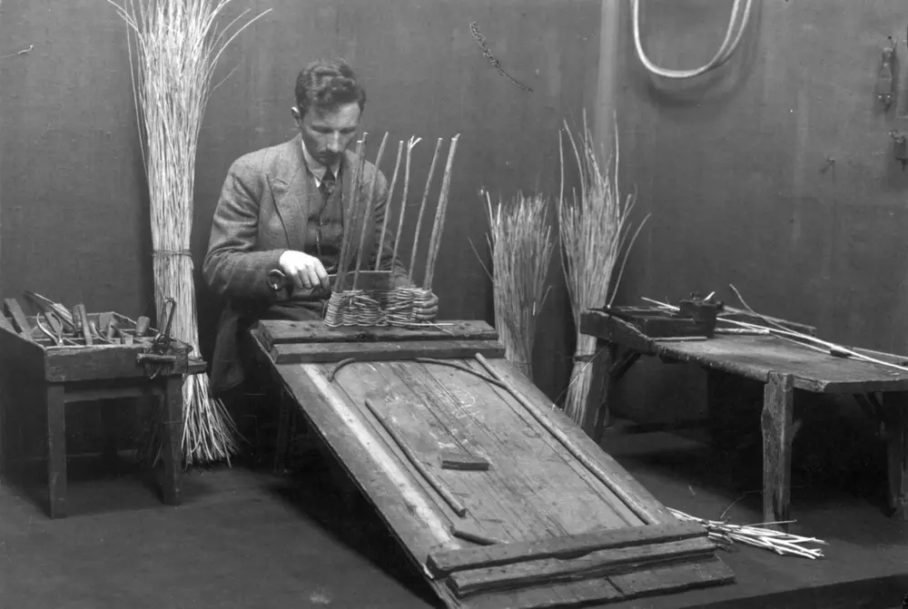 Konservator Hilmar Stigum demonstrerer i Håndverksutstillingen på Norsk Folkemuseum, 1930. Kurvmakerverkstedet i Ridehuset.