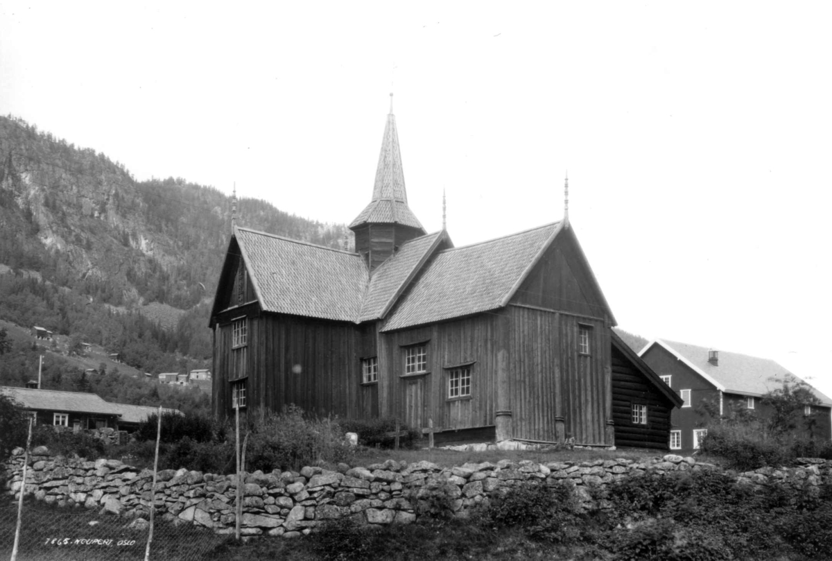 Nore stavkirke, Nore og Uvdal, Numedal, Buskerud. 1930. Kirkegård. Gravkors. Bebyggelse. Gårder, skog og åser i bakgrunnen.